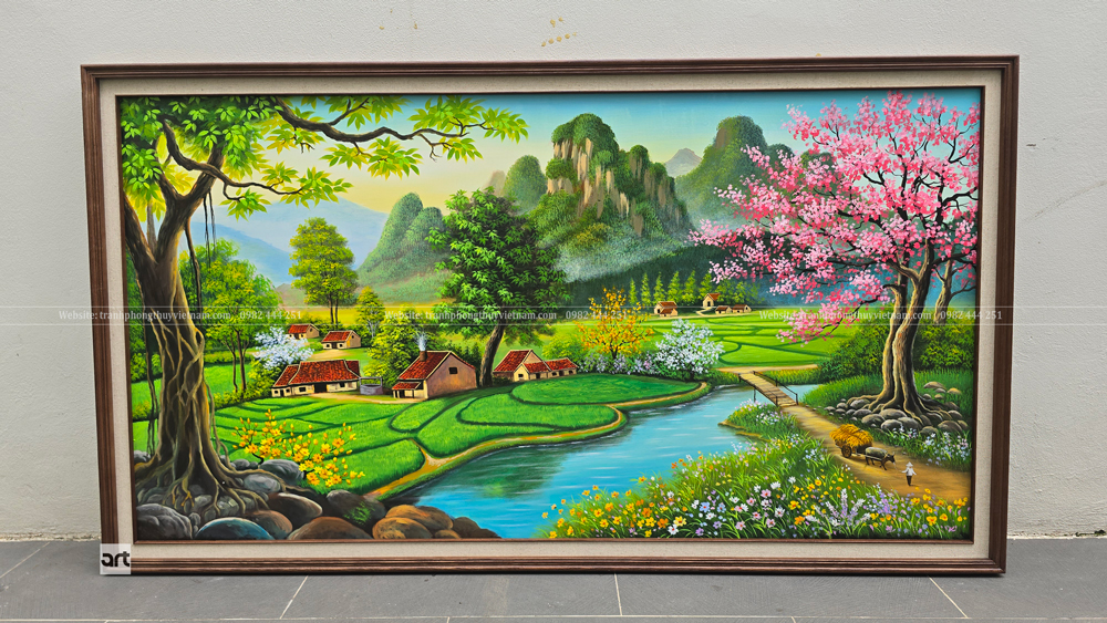 Ảnh chụp gần chính diện tranh phong cảnh làng quê ven sông với ruộng xanh, xóm nhà và cây hoa sắc hồng Ảnh chụp gần chính diện tranh phong cảnh làng quê ven sông với ruộng xanh, xóm nhà và cây hoa sắc hồng